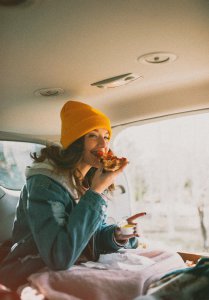 Girl eating a slice of pizza in a campervan