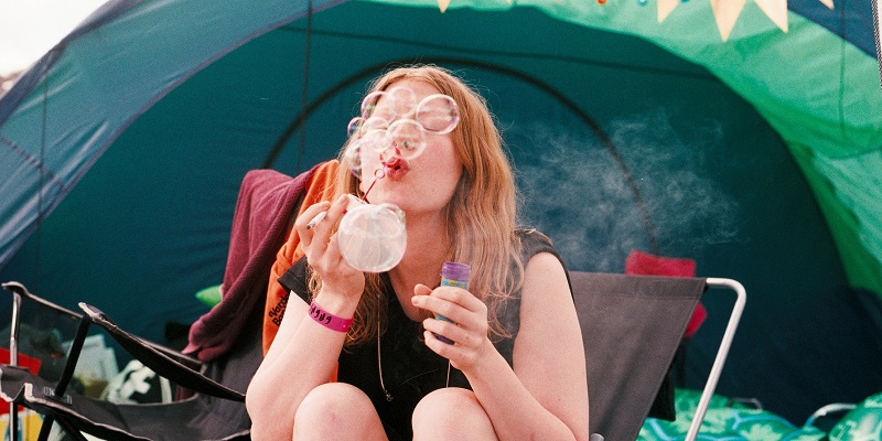 Une fille fait des bulles de savon devant sa tente